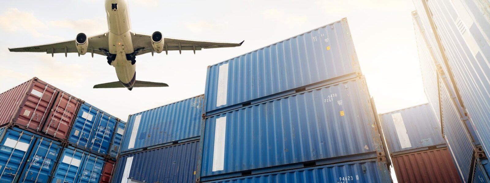 airplane flying above shipping containers in sunli 2026 03 18 04 36 02 utc