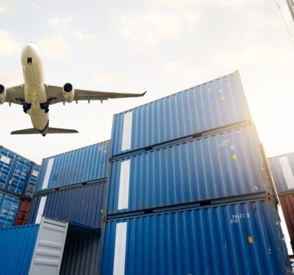 Jak zintegrować logistykę ostatniej mili ze strategią omnichannel? 1 airplane flying above shipping containers in sunli 2026 03 18 04 36 02 utc